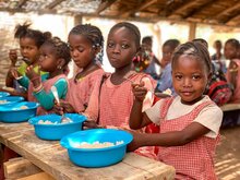 Kamissa et ses amies de l’école primaire de Koundara en Guinée prennent leur déjeuner avant de reprendre leurs cours de l’après-midi. Photo prise avant l'apparition de la COVID. PAM/Yeni Soh 