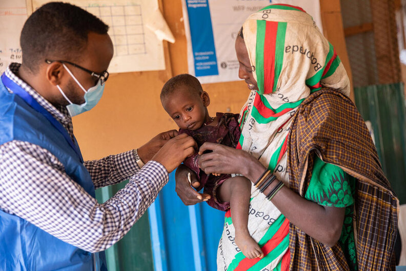 Sur cette photo, un membre du personnel du PAM s'entretient avec Mido et sa plus jeune fille Fatun au centre de traitement de la malnutrition financé par le PAM à Kabasa, au Dolow. PAM/Samantha Reinders