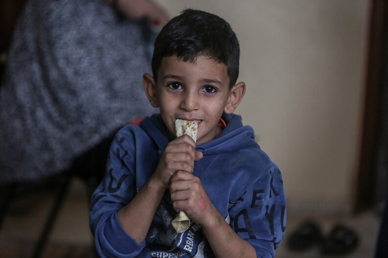 Un petit garçon, l'un des fils de Khitam, mange du pain fourni par le PAM © WFP/Ali Jadallah