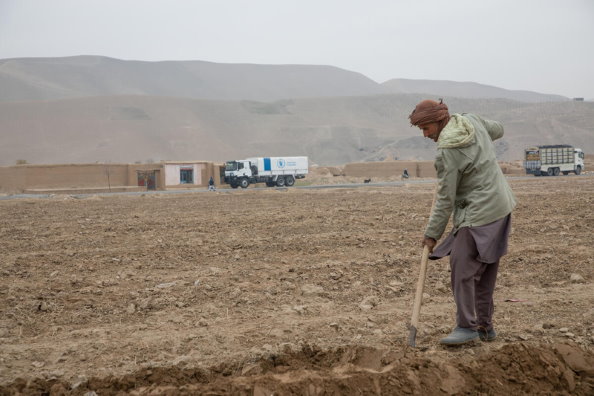 Photo: WFP/Julian Frank, Les agriculteurs de la province de Balkh avec le convoi du PAM en arrière-plan