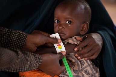  Somalia. Mother Dahera (28) holds her son Mashallah (2) while his MUAC is tested at the WFP funded Kabasa Health Center in Dolow