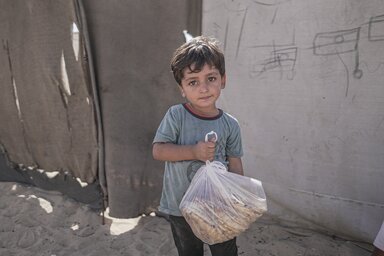 A little boy carrying a bundle of bread provided by WFP in Gaza.