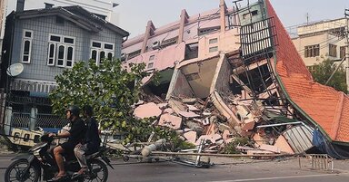 People drive on a motorbike past a collapsed building in Mandalay on March 28, 2025, after an earthquake in central Myanmar.