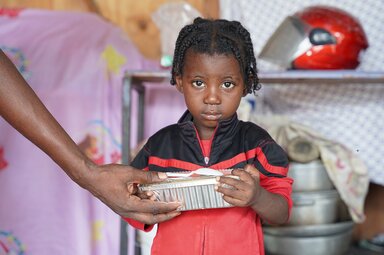 A girl receiving a hot meal at a site for internally displaced people of the Port-au-Prince commune.