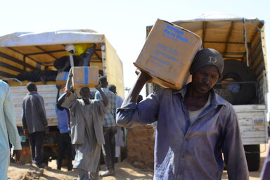 Un homme s'éloigne du camion avec de la nourriture du PAM sur l'épaule