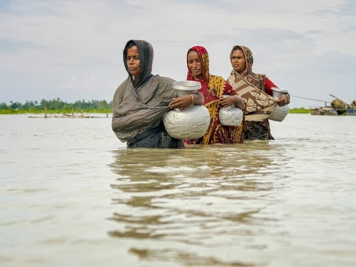 Three women walking in a flooded place