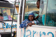A woman in a blue patterned shawl stares out of a bus. Photo: WFP/Aurore Vinot