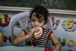 Une jeune fille mange du pain distribué par le PAM dans une école de l'UNRWA qui est un abri désigné en cas d'urgence.