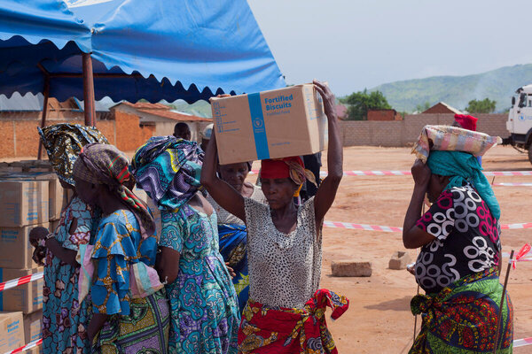Photo : PAM/Musa Abema. Une femme qui vient de recevoir de l'aide transporte une boîte de biscuits sur la tête à Sange, dans le territoire d'Uvira, en province du Sud-Kivu, en République démocratique du Congo.