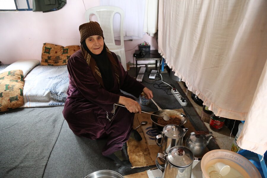 An elderly woman in Dara governorate prepares coffee in a temporary shelter.