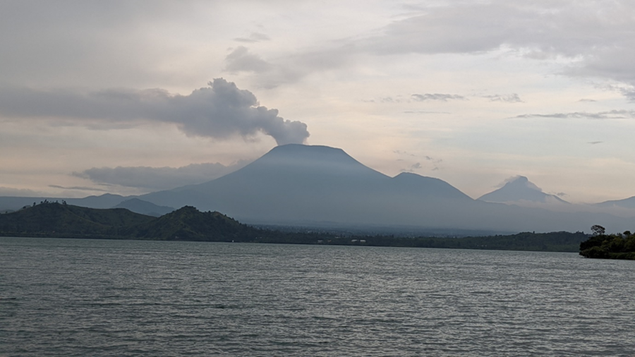 Smoke exits the volcano of Mount Nyiragongo beyond the sea.