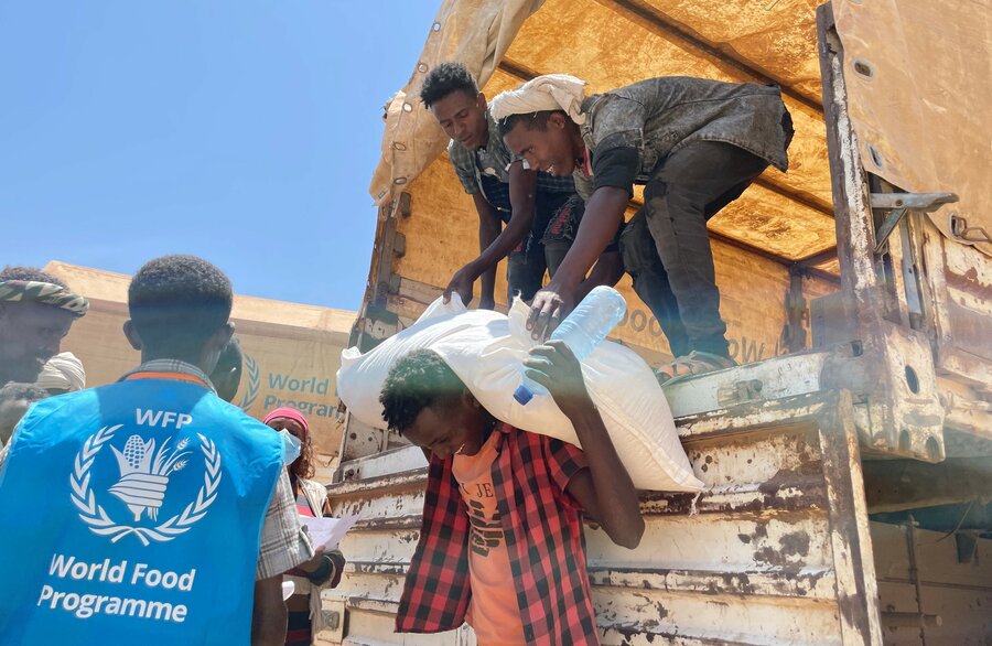 Local community members and WFP personnel unload bags of wheat from a truck to those in need in the town of Adi Millen in Tigray. Photo: WFP/Claire Nevill
