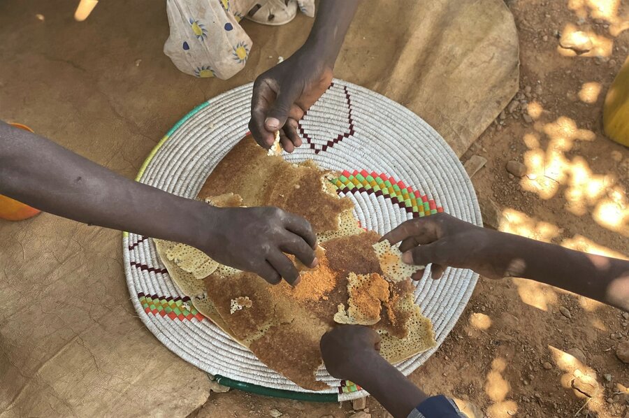 Aster's family share enjoy a dish of injera with spices, a local favourite, which was made using wheat provided by WFP. Photo: WFP/Claire Nevill