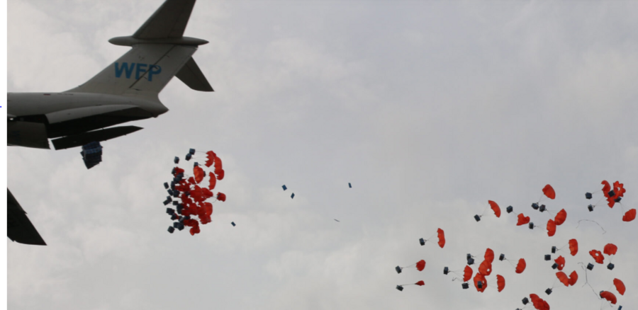 orange parachutes dropping out of plane against cloudy sky