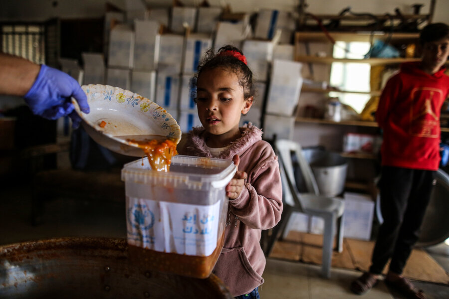 A little girl receives WFP food in Deir Albalah, in central Gaza. Famine is imminent in parts of the enclave however, as humanitarian aid piles up on its borders due to access constraints. Photo: WFP/Ali Jadallah 