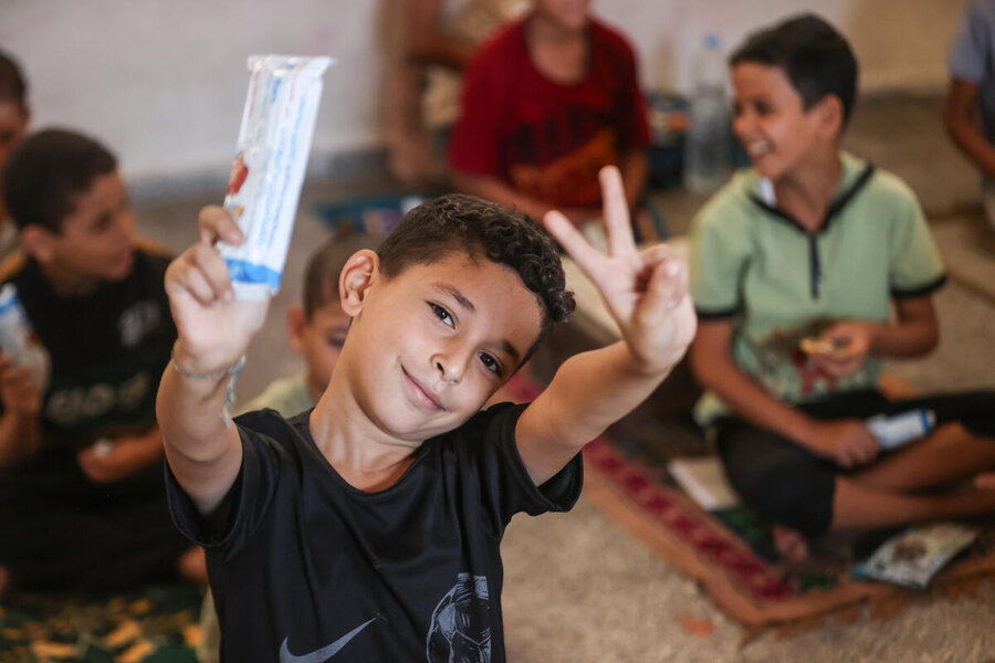 Children receive date bars from WFP in a makeshift classroom faciliated by UNWRA in Khan Younis in Gaza where persistent evactuation orders compound the difficulties people face. Photo: WFP/Ali Jadallah