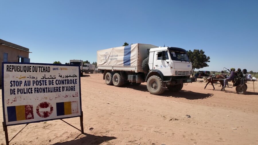 A white truck with a blue WFP stripe drives past signpost announcing Chad border checks in French