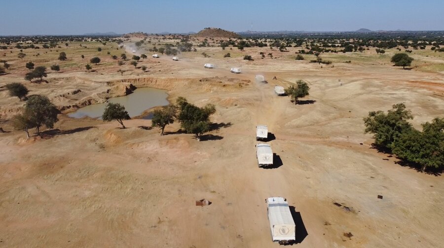 Aerial shot of white trucks cutting across desert dotted with bushes