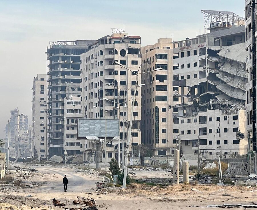  A solitary figure walks among bombed, white residential towers in deserted Gaza City