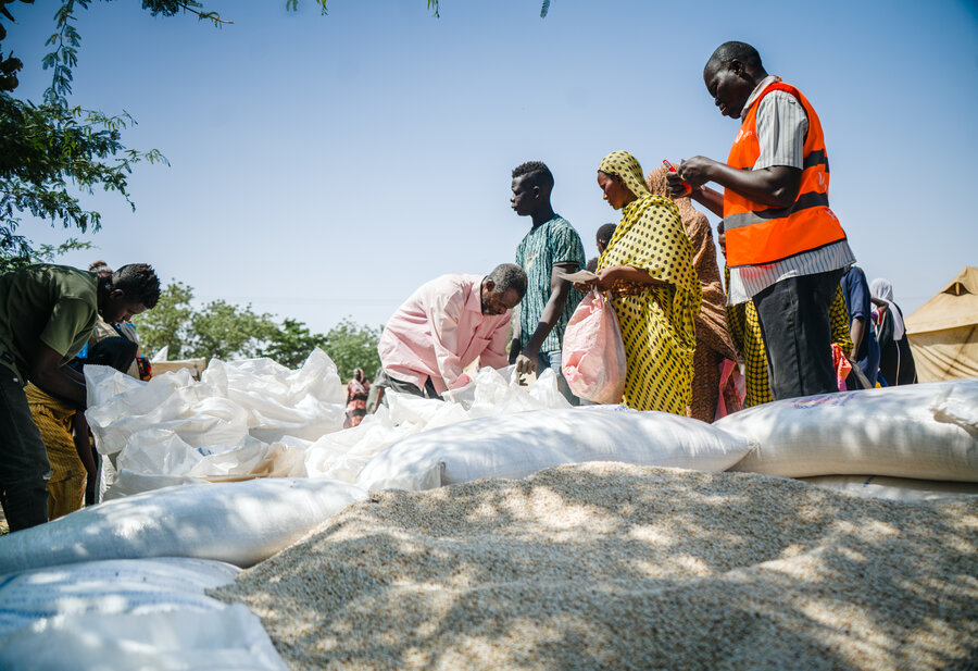 Workers distribute WFP food at a displacement camp in eastern Sudan. Hunger is surging in the country, with famine confirmed in some places. WFP/Abubakar Garelnabei