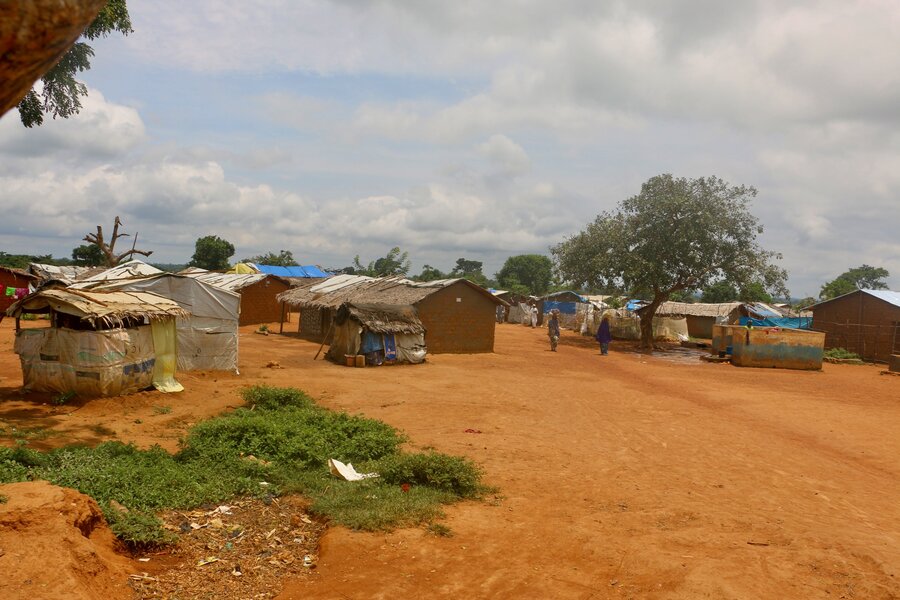 A refugee camp of mud and straw houses sits on dusty red land, with a few trees in the background. Photo: WFP/Mayramou Madaki