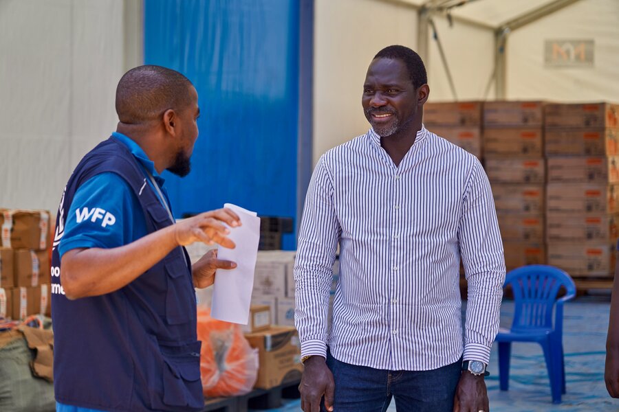 Two WFP employees confer over Ebola response; one wears a blue WFP T-shirt and vest, and the other a striped, button-down shirt. Photo: WFP/Gedeon Mugisa
