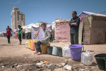 Photo : PAM/Photothèque. Des Palestiniens déplacés font la queue et attendent de remplir leurs bidons d'eau dans la ville de Gaza.