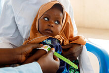 PAM/Nommiyid Chantu. Une mère reçoit un traitement pour la malnutrition aiguë modérée (MAM) de son bébé dans une clinique nutritionnelle soutenue par le PAM, au camp 1000 IDP de Dikwa, dans le nord-est du Nigeria. Un examen MUAC de 12 sur l'échelle jaune indique que Zainab souffre de malnutrition aiguë modérée.