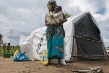 WFP/Grant Lee Neuenburg, Femme et son bébé debout devant une tente dans un camp de réinstallation, Cabo Delgado, Mozambique.