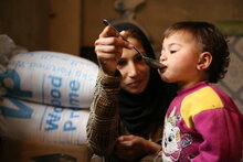 Photo: PAM/Abeer Etefa, Une femme déplacée avec sa famille de Douma dans la campagne de Damas à Adra, nourrit sa fille de 18 mois pour le déjeuner.