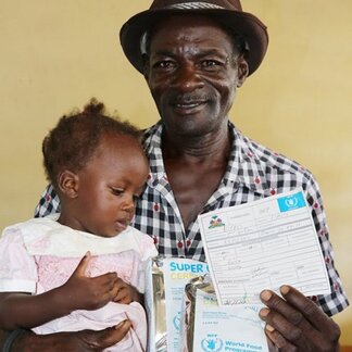 Un père reçoit du PAM des aliments fortifiés et riches en nutriments pour sa fille.