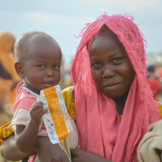 Une mère et son enfant qui tient un biscuit distribué par le PAM