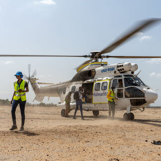 Une femme en gilet s'éloignant d'un hélicoptère du PAM sur le point de décoller.