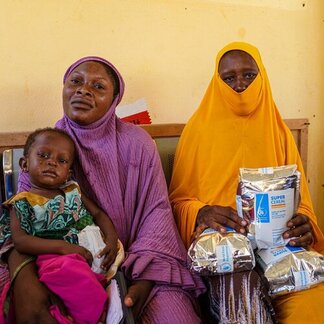 Des accompagnants et un enfant reçoivent des aliments nutritifs spécialisés dans un établissement de santé, afin de soutenir le traitement et la prévention de la malnutrition.
