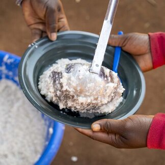 Chrissie and Livines serve the school meals to the students of one of the schools supported by WFP through the home-grown school meals programme. 
