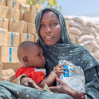 Une mère et son enfant avec des aliments nutritifs préparés, sur un site de distribution du PAM. Photo : PAM /Petroc Wilson