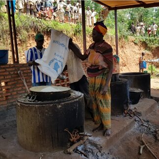 Une femme prépare des repas scolaires dans une cuisine.