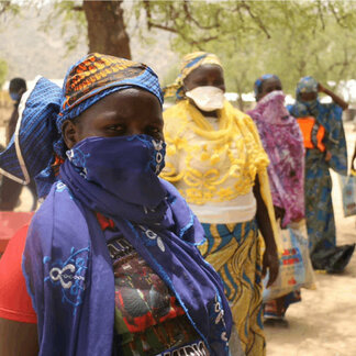 Femmes faisant la queue pour recevoir l'aide alimentaire distribuée par le PAM en réponse aux crises climatiques et violentes au Cameroun.