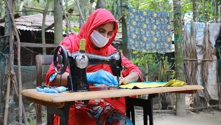 Pendant la pandémie de covid-19, à Cox's Bazar, au Bangladesh, le PAM s'est engagé avec des femmes de la communauté d'accueil et des réfugiés rohingyas, par le biais de son programme d’existence, à fabriquer des masques qui ont été distribués par le gouvernement local et les agences humanitaires, en leur donnant une allocation mensuelle, une formation à un emploi commercialisable et des connaissances financières, ainsi qu'une bourse pour démarrer une entreprise. PAM/Nalifa Mehelin